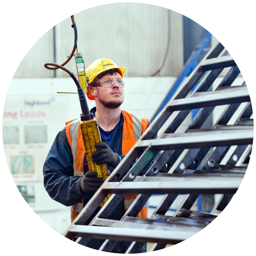 Man with yellow hard hat, with orange hi-viz waistcoat using lift controls