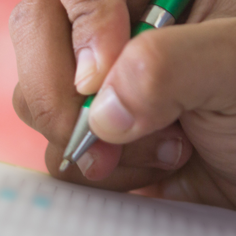 A hand holding a pen writing on paper