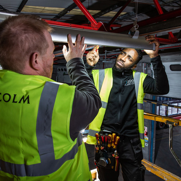 Two men installing an overhead large room ceiling light