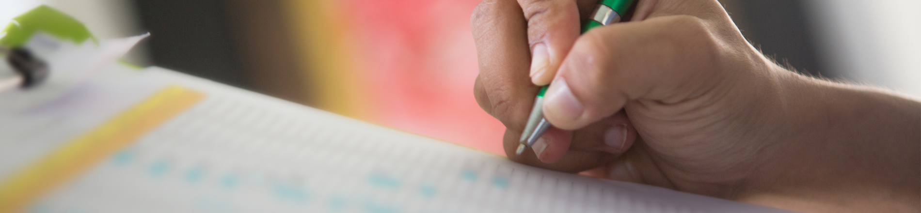 A hand holding a pen writing on paper