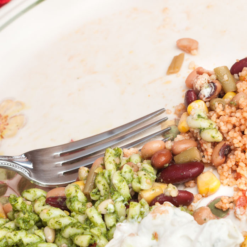 A person scraping food waste from a plate