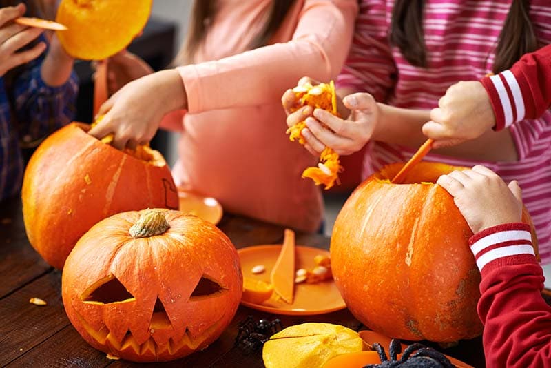 Children carving pumpkins by hand