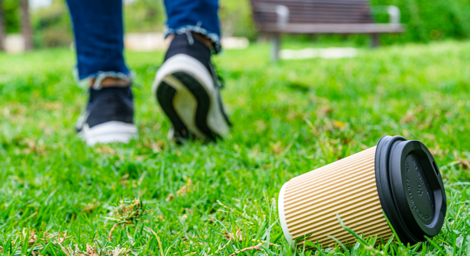 A person walking away from a littered disposable cup