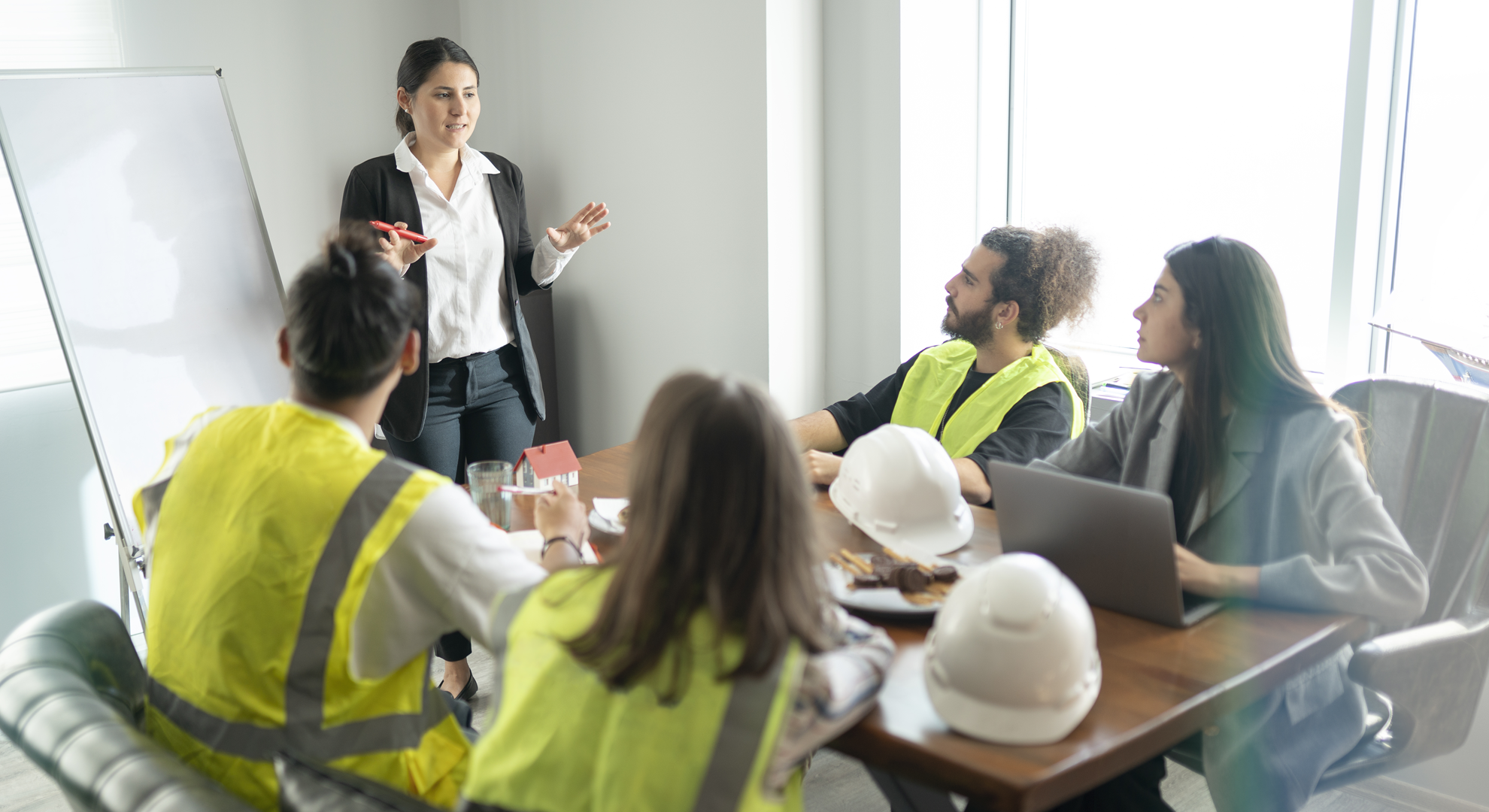 A group on construction workers sitting around a table listening to a presentation from a colleague