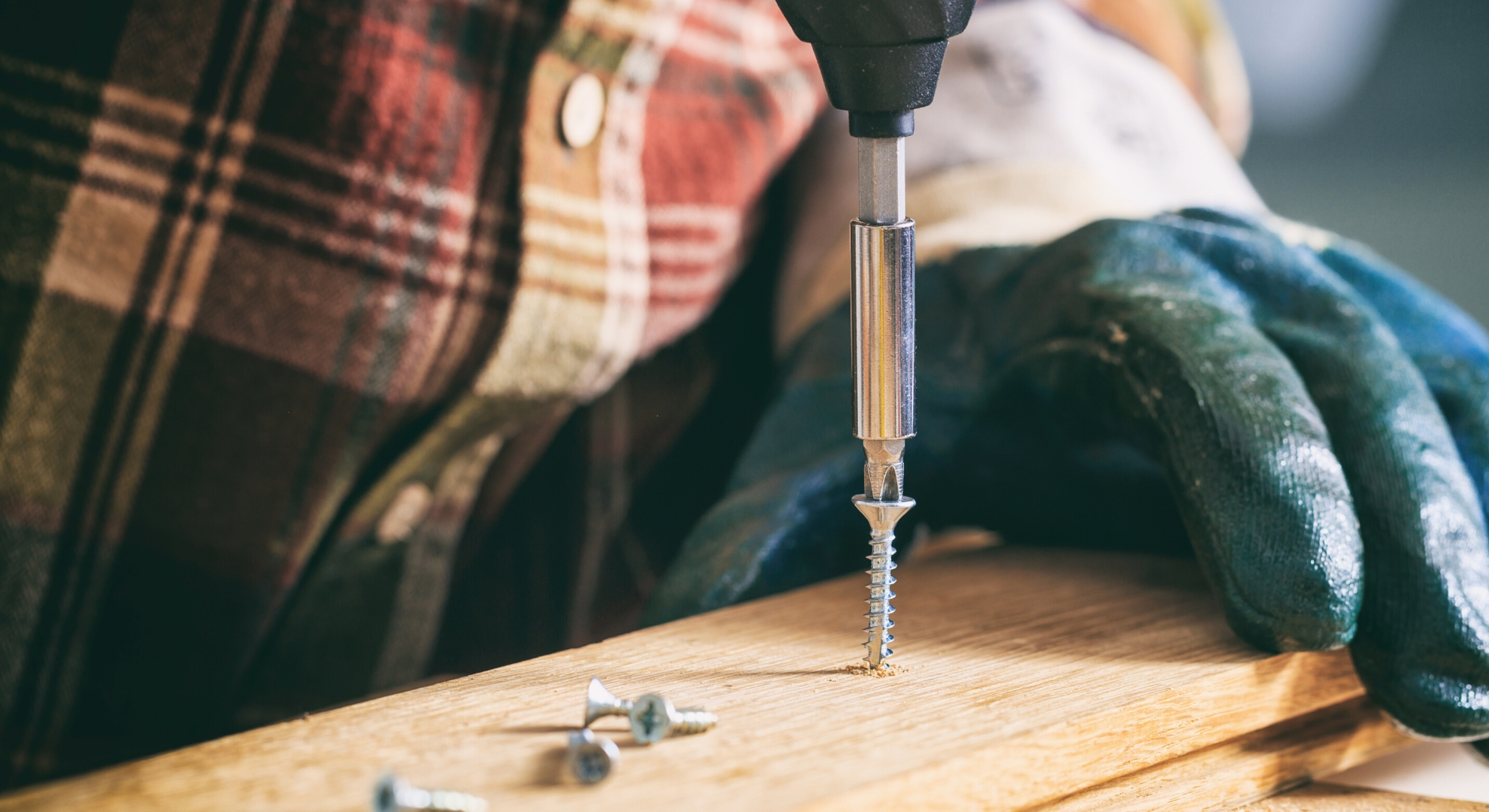 A person screwing a screw into a piece of wood