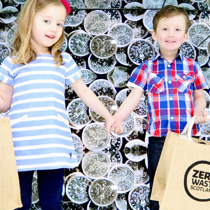 Two young children with reusable carrier bags