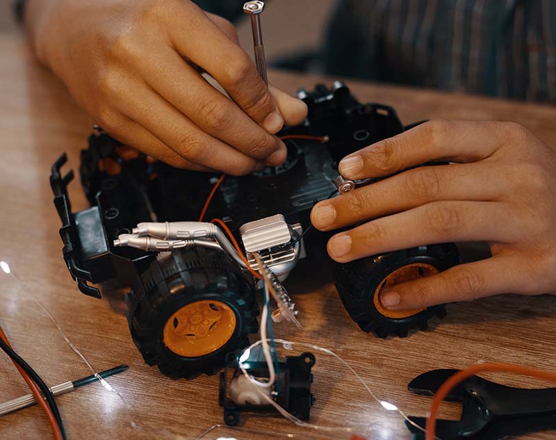 Child repairing a toy electric car with a screwdriver sign post.jpg