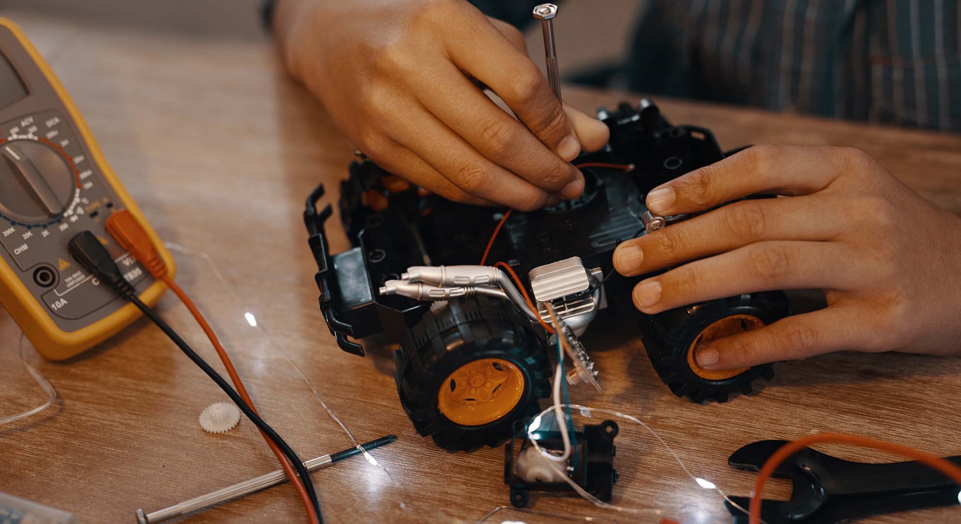 Child repairing a toy electric car with a screwdriver