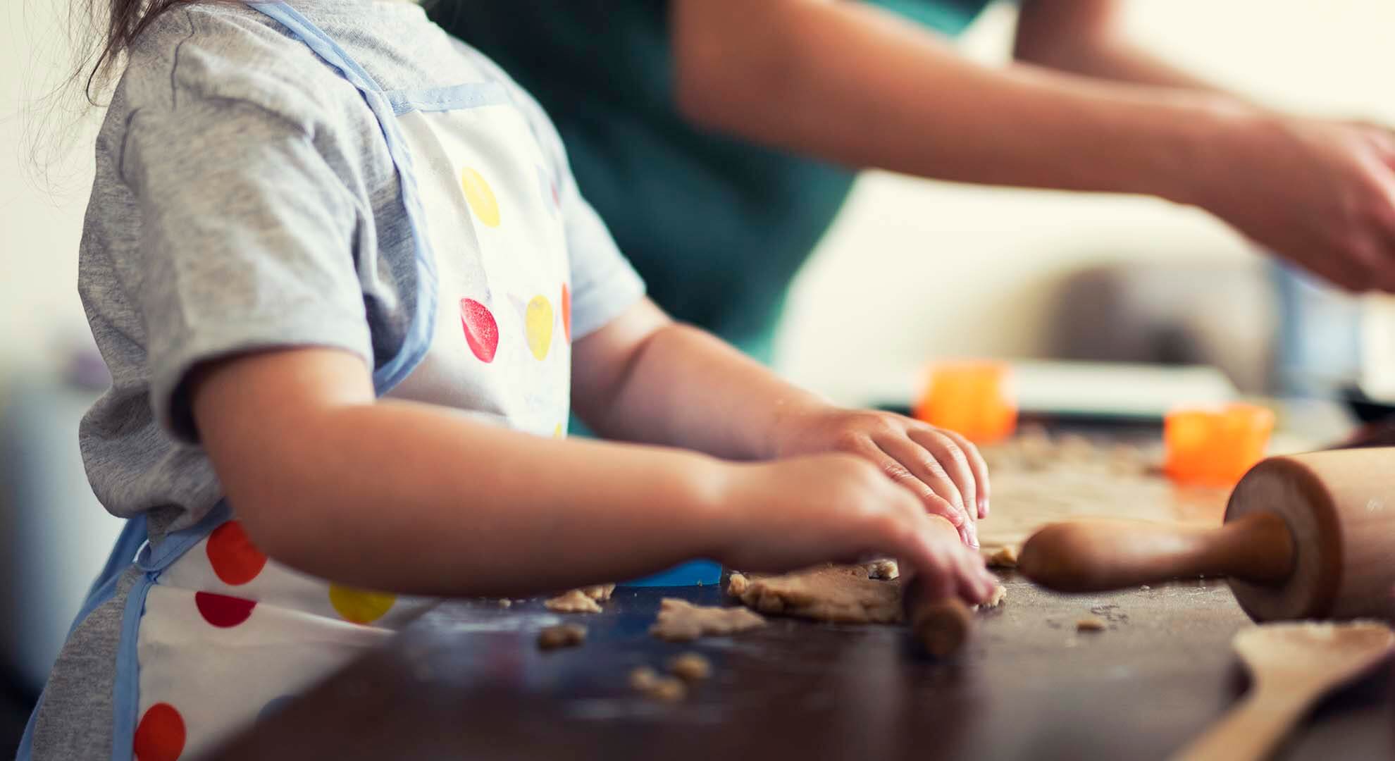 Child using a rolling pin with dough