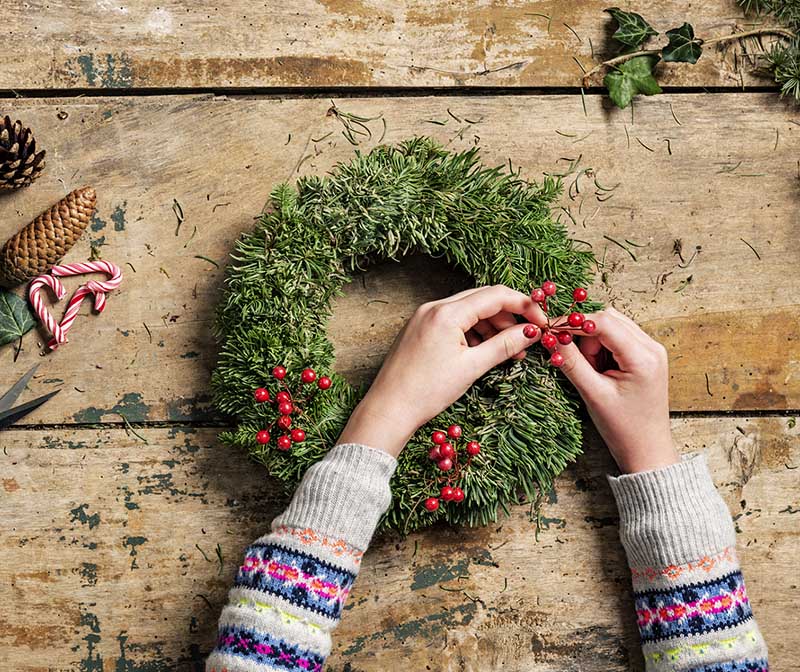 Making a Christmas wreath decoration with tree clippings, berries and pine cones