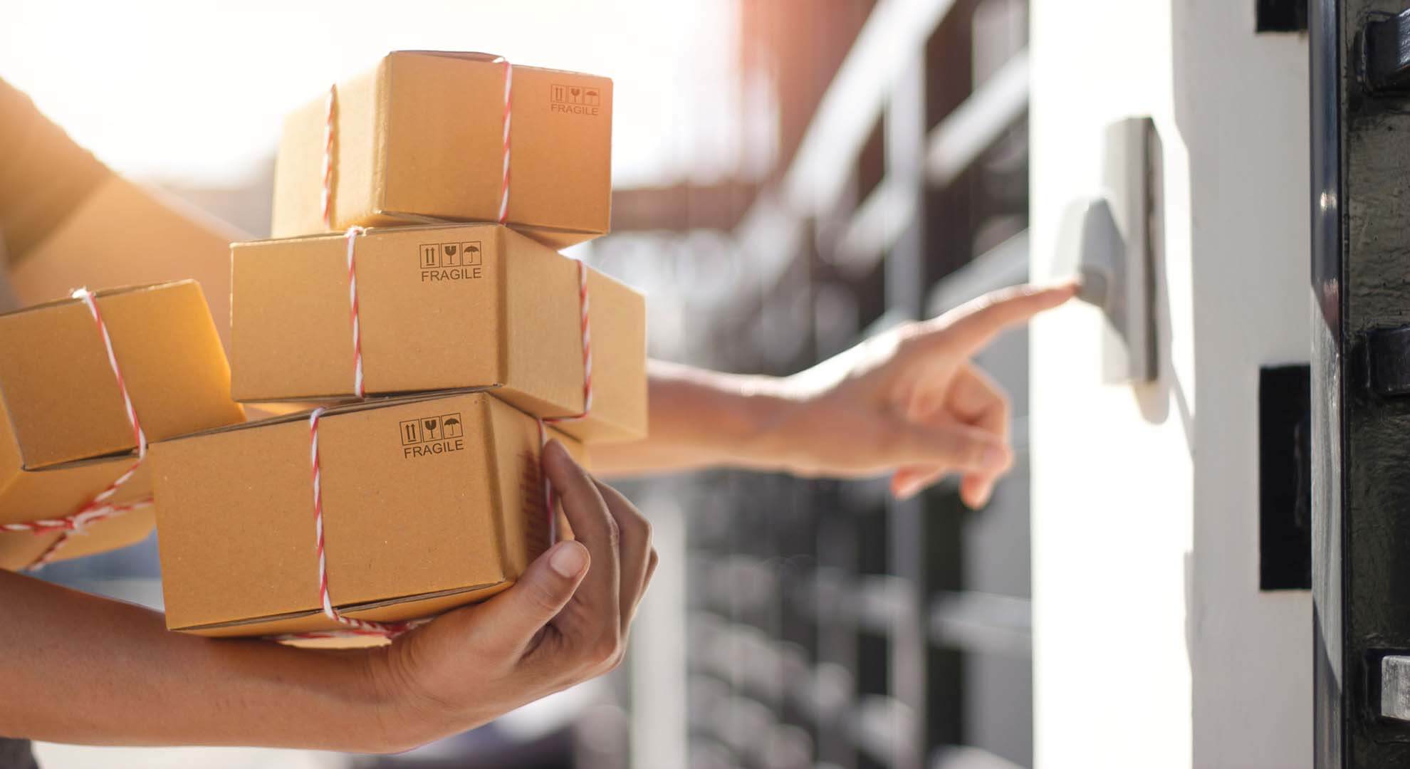 Person pressing a doorbell to deliver a pile of parcels