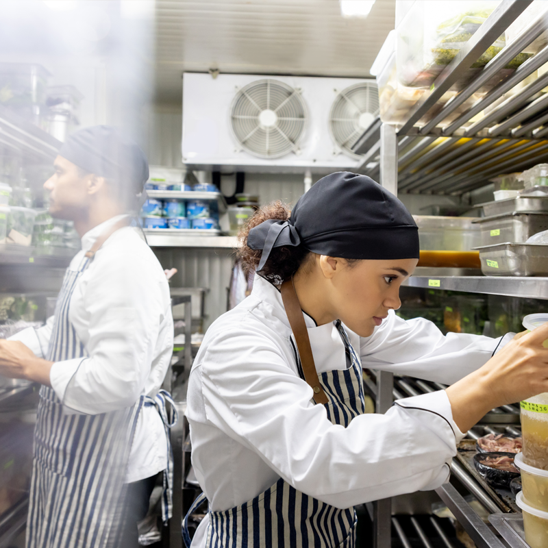 Two chefs in a cool storage area looking at food