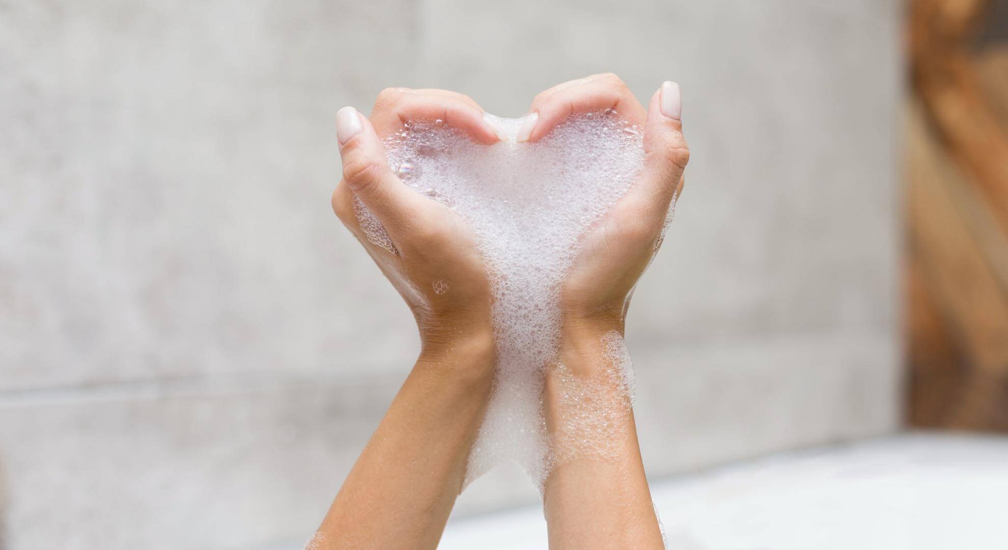 Person holding bubbles in the shape of a loveheart