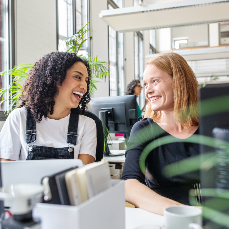 Two people sitting in front of a computer smiling