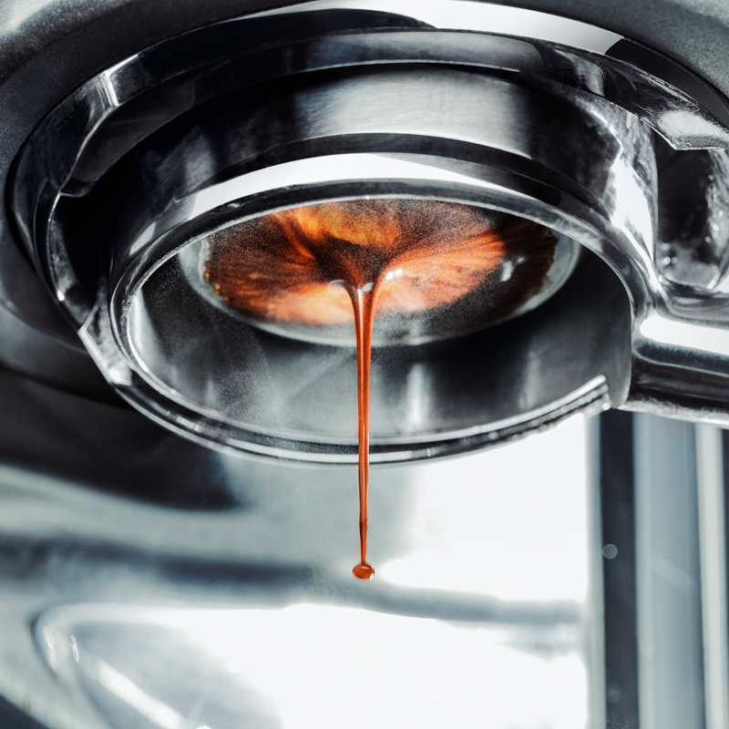 A coffee machine with fresh coffee flowing out of it