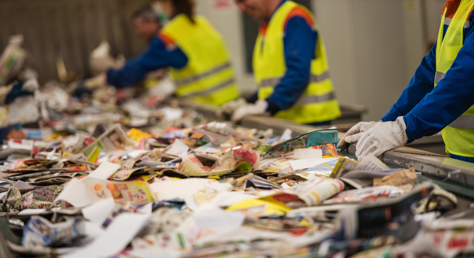 Staff working in from of a conveyor belt of materials at a Material Recover Facility