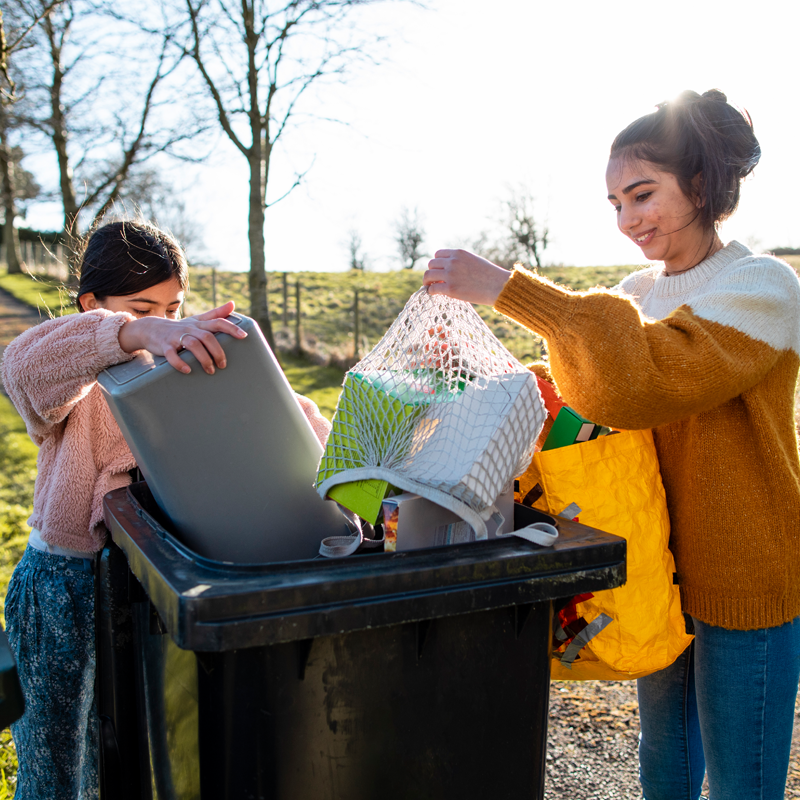 People putting recycling into a wheelie bin