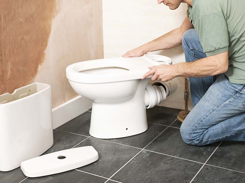 A person working to remove a toilet 