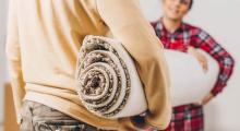 2 people holding a rolled up rug