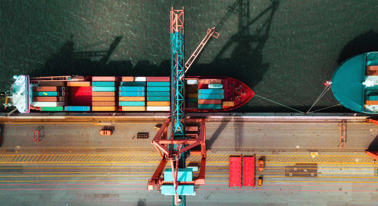 A high altitude shot of shipping containers arriving at a port