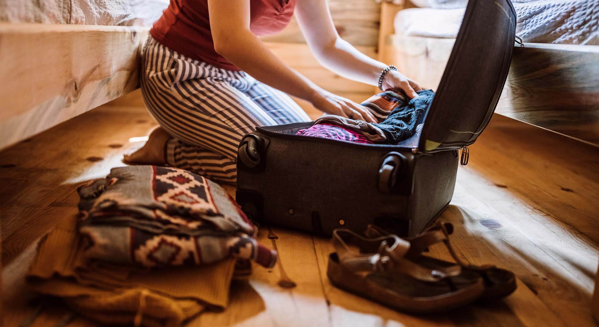 a person putting clothes into a suitcase