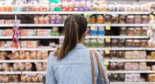 A women is standing facing a supermarket shelf