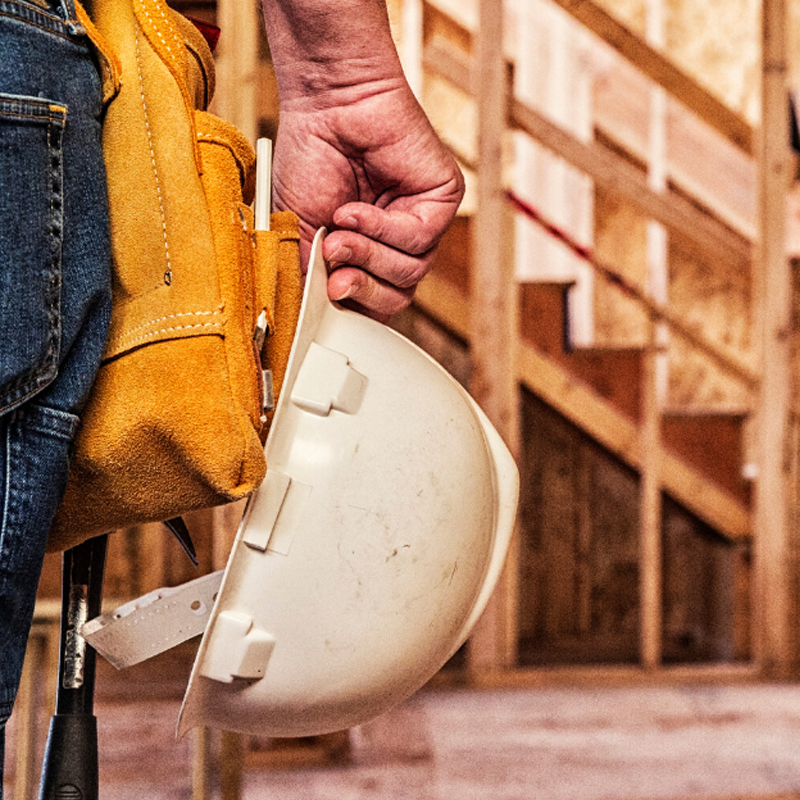 Conceptual image of a construction project, with a worked holding a safety hat