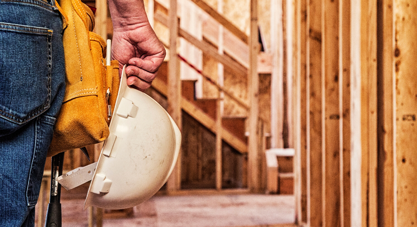 Conceptual image of a construction project, with a worked holding a safety hat