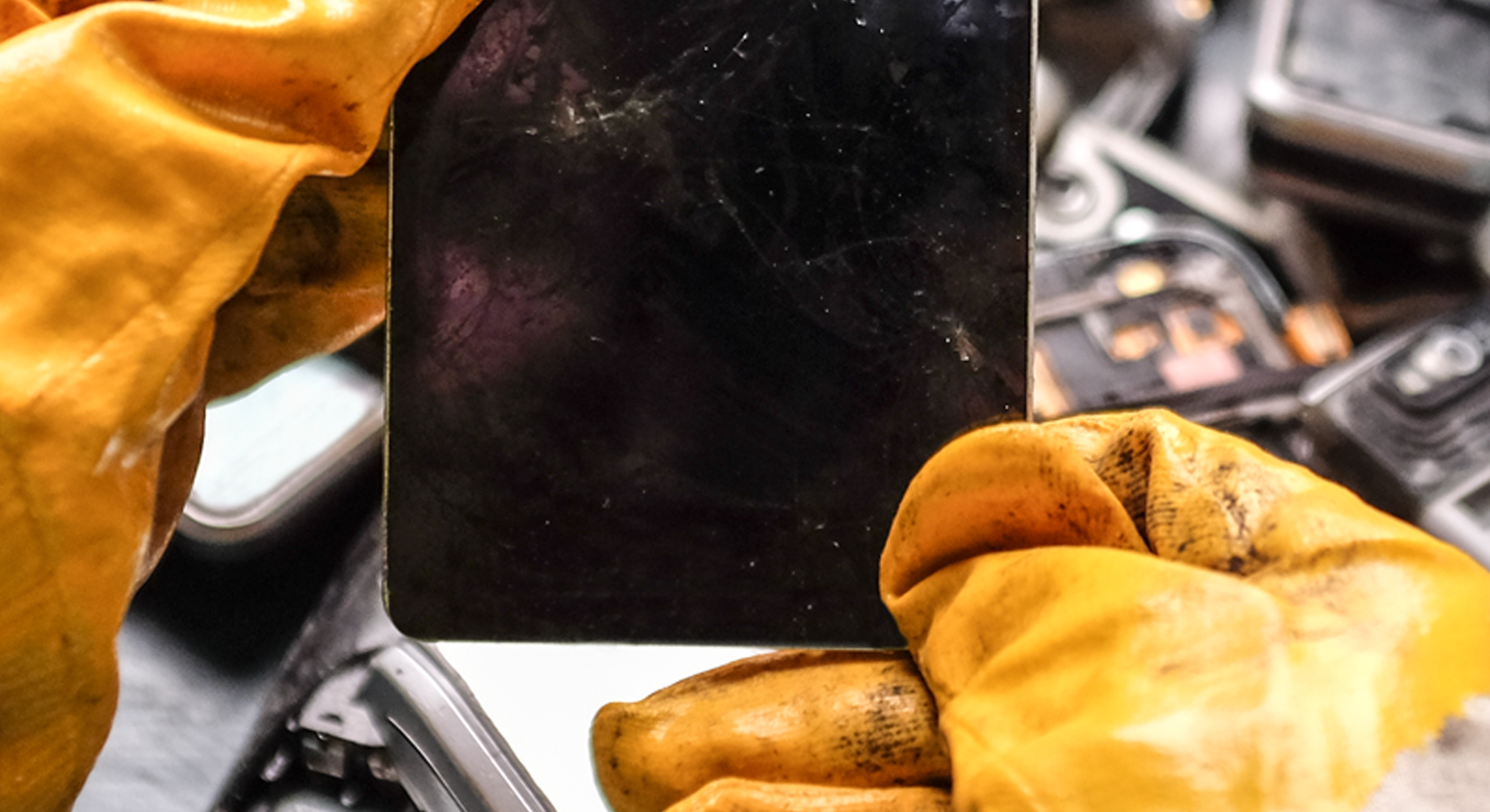 Hands with protective gloves holding a metal component