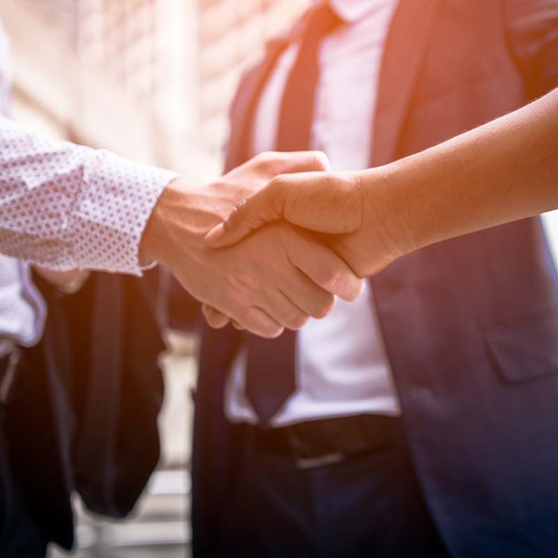 Photo of three people in suits shaking hands