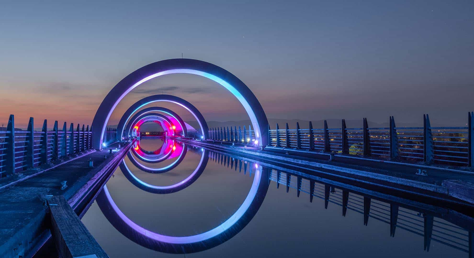 Photo looking across the rings of the Falkirk wheel lit up at dusk.