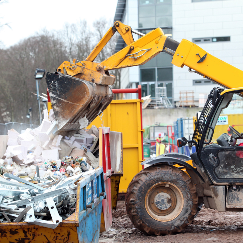 Construction worker using tipper to sump construction waste in a skip