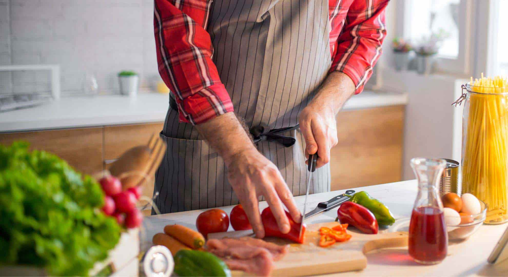 A person wearing an apron chopping vegetables