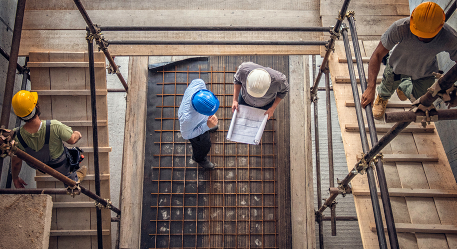 Construction site with workers looking at plans and undertaking construction work