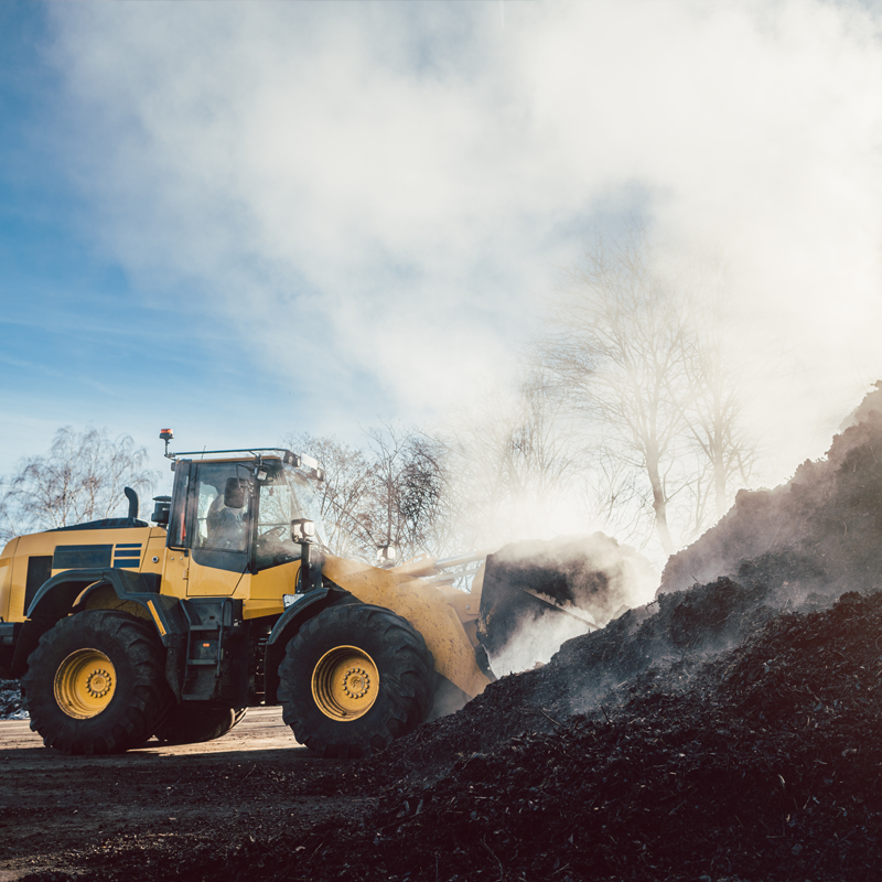 A large digger moving massive amounts of industrial compost