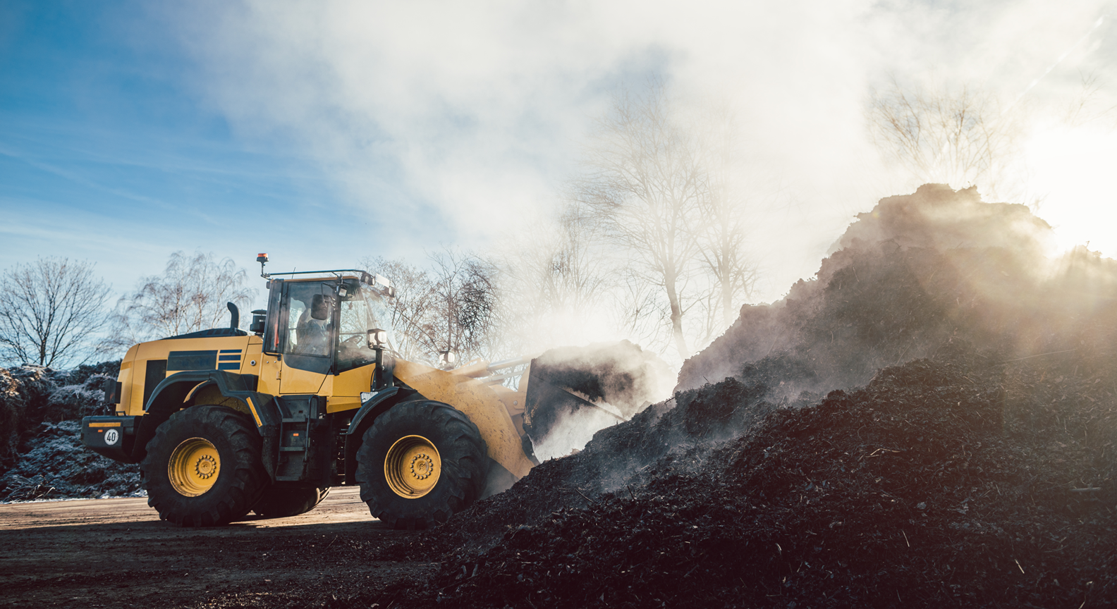 A large digger moving massive amounts of industrial compost