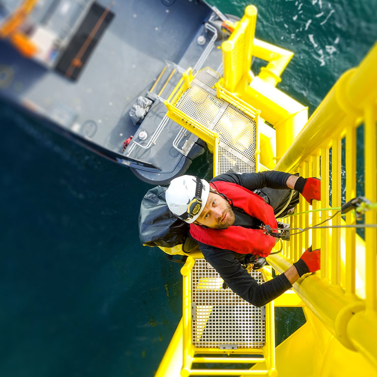 A person climbing a yellow ladder at sea