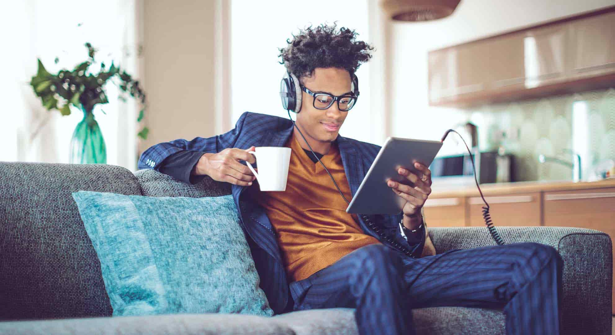 Photo of a man in a suit sitting on a sofa listening to a podcast