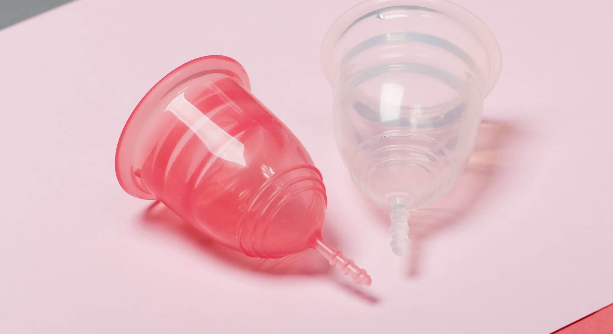 Two menstrual cups close-up on a pink background